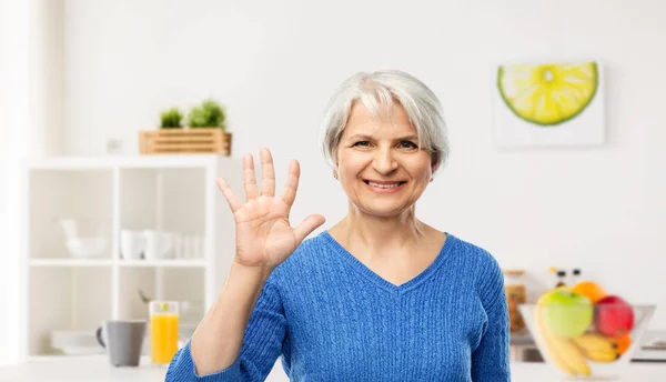 Улыбающаяся пожилая женщина показывает свою ладонь на кухне — стоковое фото