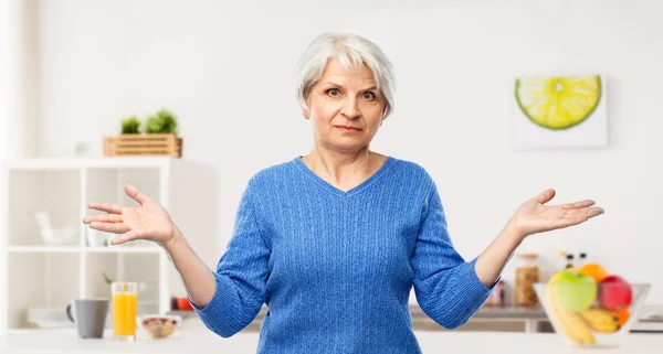 Mujer mayor que se encoge de hombros en la cocina — Foto de Stock