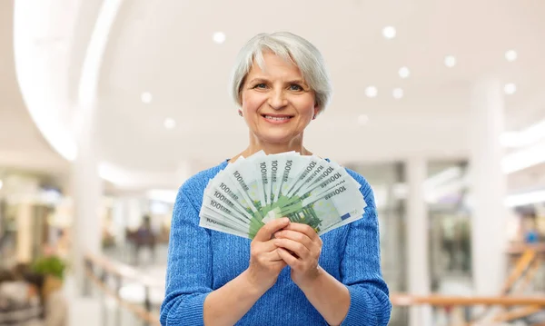 Mujer mayor con dinero en euros en el centro comercial — Foto de Stock