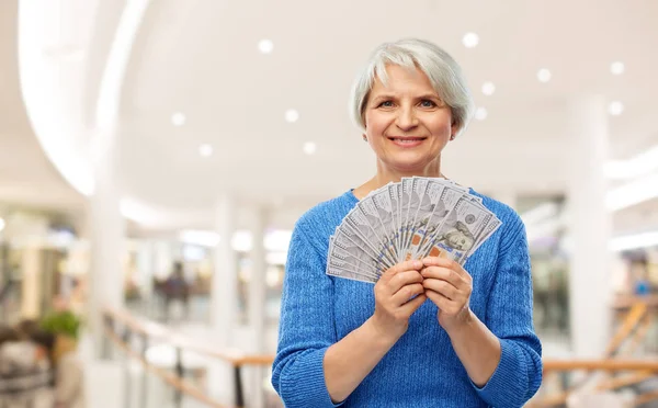 Mujer mayor con dinero en dólares en el centro comercial — Foto de Stock