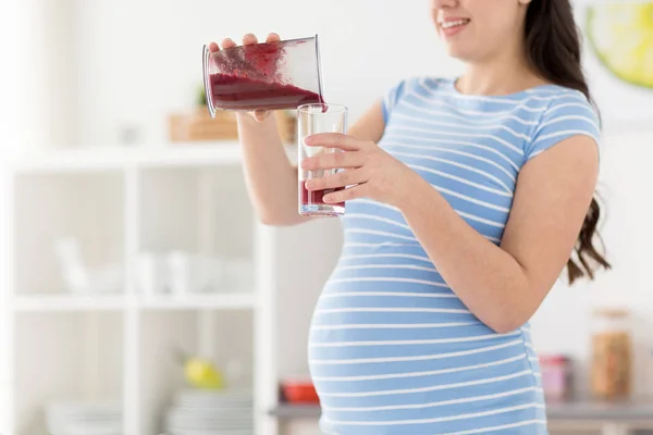 Mulher grávida derramando smoothie fruta em casa — Fotografia de Stock