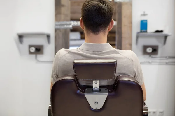 Man sitting in chair at barbershop or hair salon — Stock Photo, Image