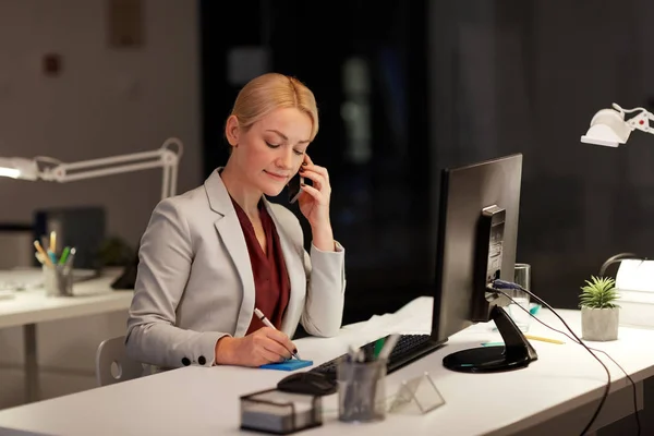 Empresária chamando sartphone no escritório da noite — Fotografia de Stock