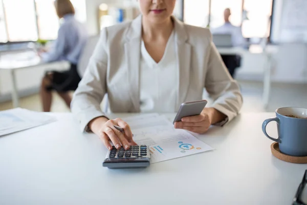 Mujer de negocios con calculadora y smartphone —  Fotos de Stock