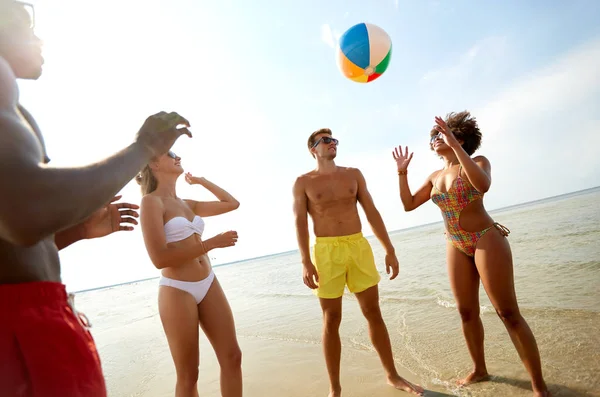 Happy přátelé hrát míč v létě beach — Stock fotografie