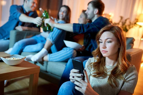 Triest jonge vrouw met smartphone bij thuis partij — Stockfoto