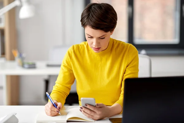 Affärskvinna med smartphone och anteckningsbok — Stockfoto