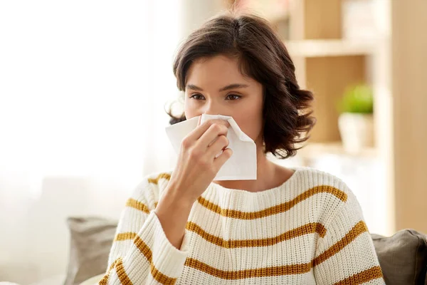 Sick woman blowing nose in paper tissue at home — Stock Photo, Image