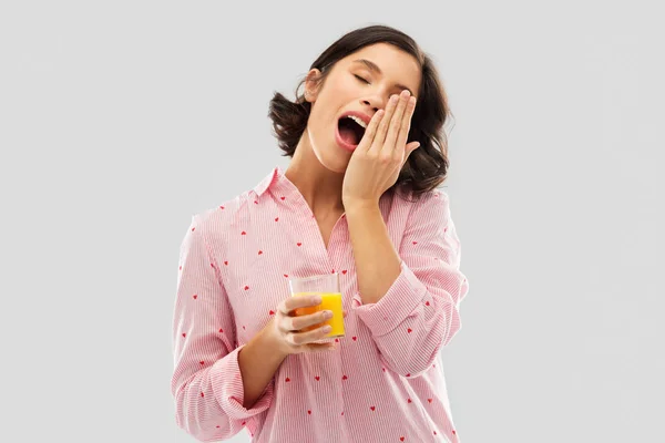 Glücklich gähnende junge Frau im Pyjama mit Saft — Stockfoto