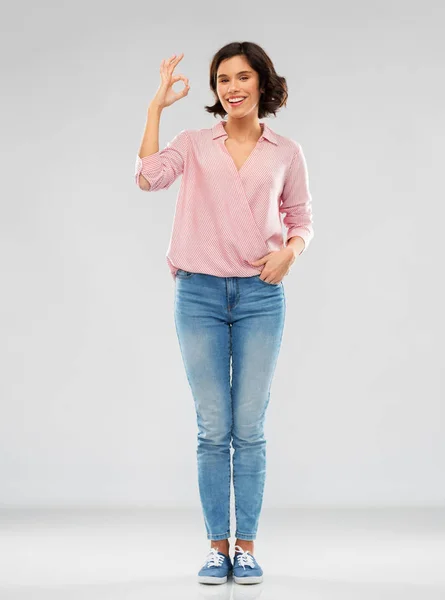 Junge Frau in gestreiftem Hemd und Jeans zeigt ok — Stockfoto