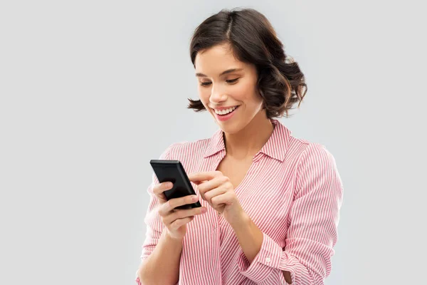 Młoda kobieta w pasiastej koszuli za pomocą smartfona — Zdjęcie stockowe