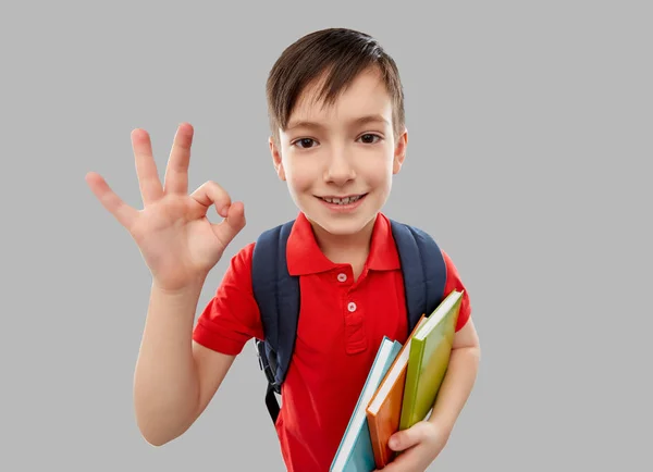 Μαθητής αγόρι με βιβλία και σχολική τσάντα δείχνει OK — Φωτογραφία Αρχείου