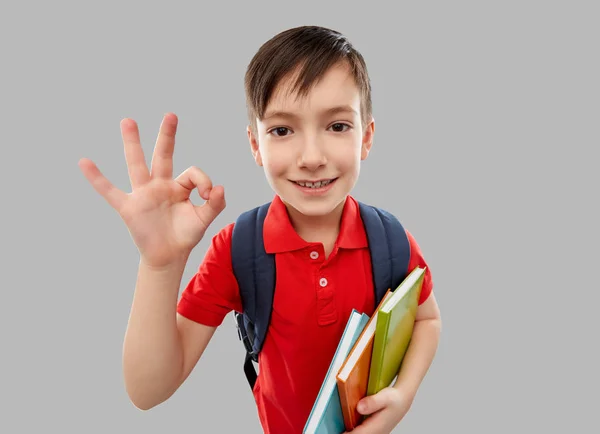 Élève garçon avec livres et sac d'école montrant ok — Photo