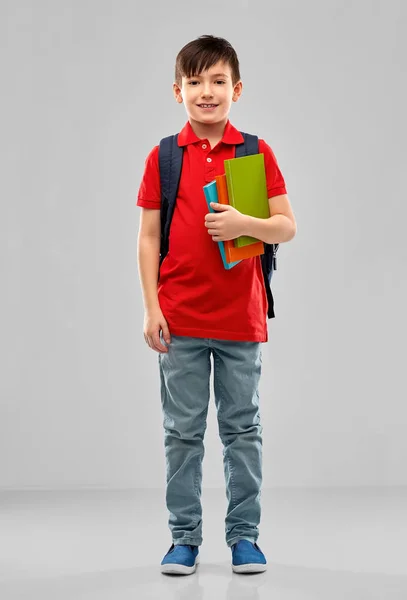 Uśmiechnięty uczeń chłopca z książkami i torbą szkolna — Zdjęcie stockowe