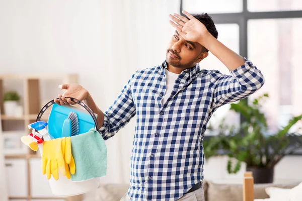 Tired man with bucket of cleaning stuff at home — Stock Photo, Image