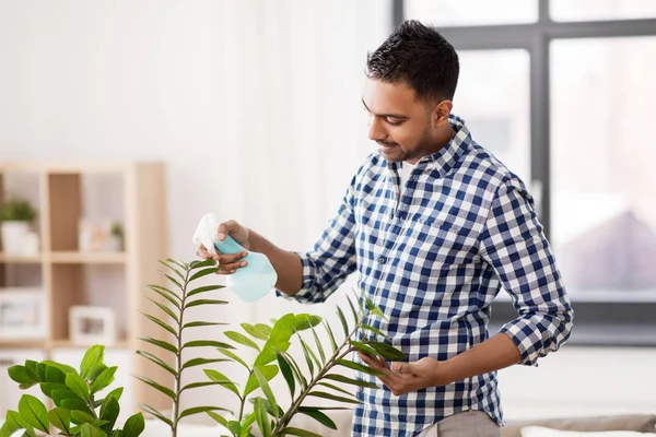 Indiase man spuiten kamerplant met water thuis — Stockfoto