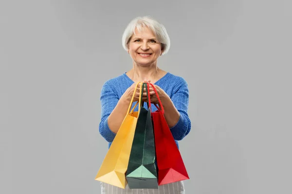 회색 위에 쇼핑백을 들고 있는 노인 — 스톡 사진