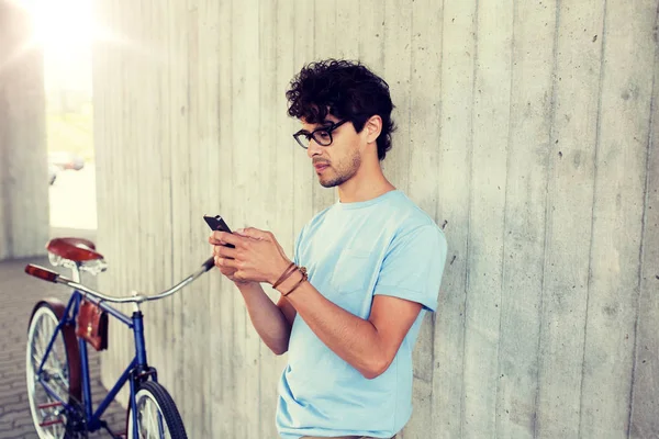 Hombre con teléfono inteligente y bicicleta de engranaje fijo en la calle —  Fotos de Stock