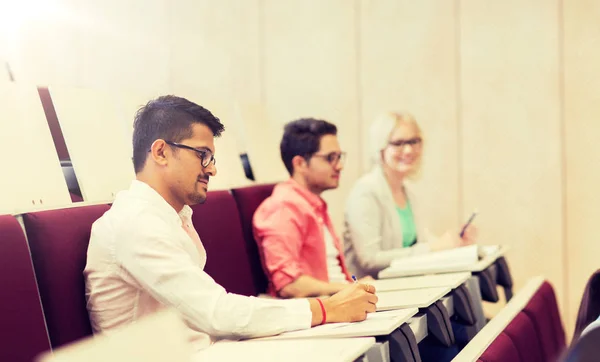 Grupo de estudiantes con cuadernos en la sala de conferencias — Foto de Stock