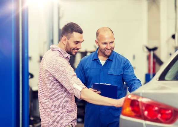 Auto mekaniker med Urklipp och man på bilverkstad — Stockfoto