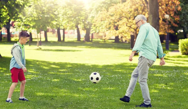 Старик и мальчик играют в футбол в летнем парке — стоковое фото