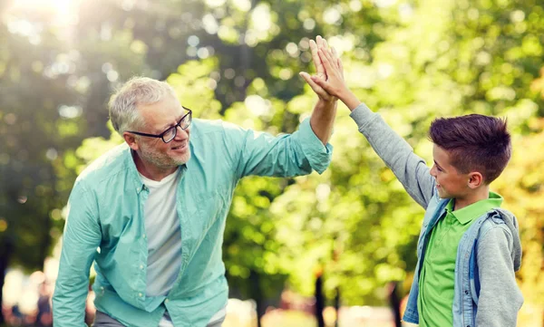 Old man and boy making high five at summer park — Stock Photo, Image