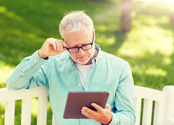 Starszy człowiek z komputera typu tablet w lato park — Zdjęcie stockowe