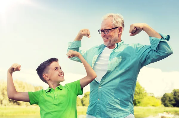Счастливый дедушка и внук показывать мышцы — стоковое фото