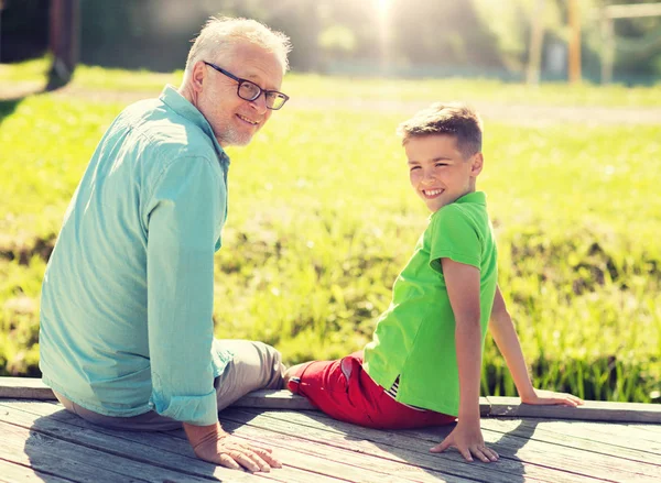 Grandfather and grandson sitting on river berth — Stock Photo, Image