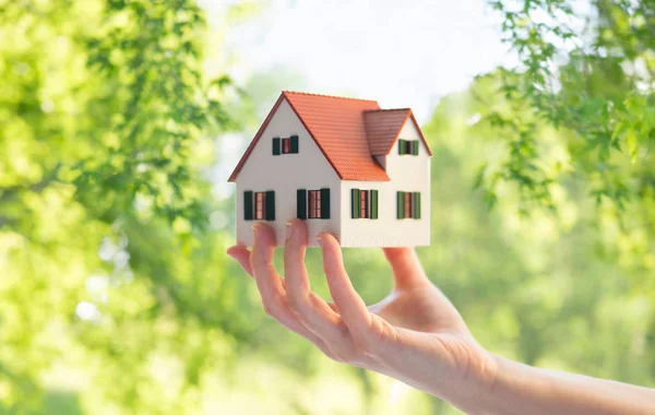 Close up de mão segurando casa ou modelo de casa — Fotografia de Stock