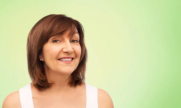 Portrait of smiling senior woman over lime green — Stock Photo, Image