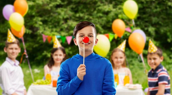 Menino feliz com nariz de palhaço vermelho na festa de aniversário — Fotografia de Stock