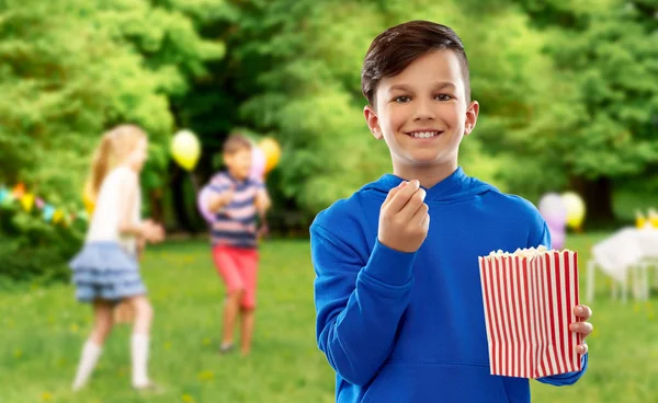 Leende pojke äter popcorn på födelsedagsfest — Stockfoto