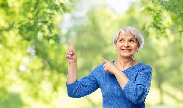 Sorridente donna anziana che punta il dito verso qualcosa — Foto Stock