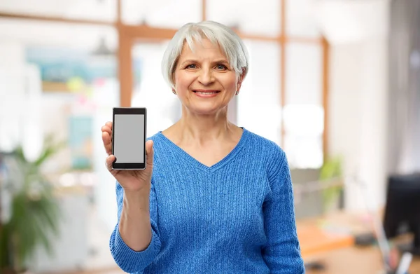 Улыбающаяся пожилая женщина показывает смартфон — стоковое фото
