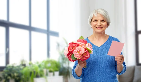 Boldog idős nő virággal és üdvözlőlap — Stock Fotó