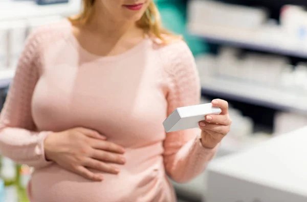 Mulher grávida escolhendo remédio na farmácia — Fotografia de Stock