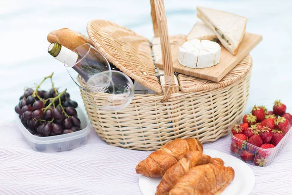 Cestino da picnic, bicchieri di cibo e vino sulla coperta — Foto Stock