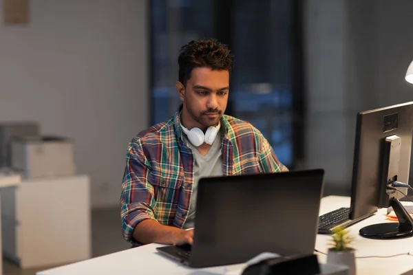 Creative man with laptop working at night office — Stock Photo, Image