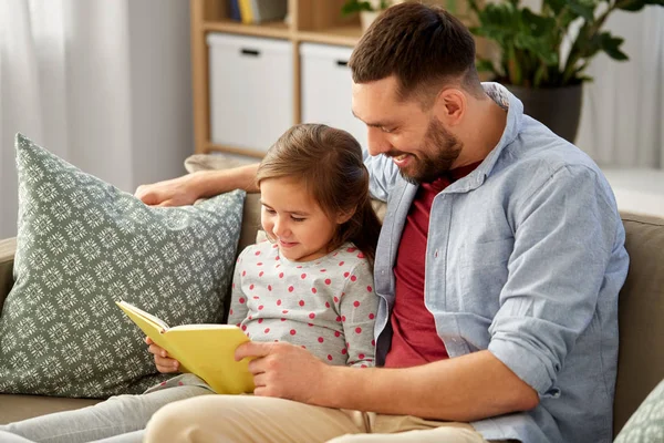 Happy father and daughter reading book at home — Stock Photo, Image