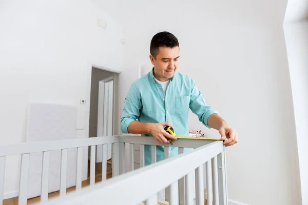 Padre con tablet pc e righello misura lettino per bambini — Foto Stock