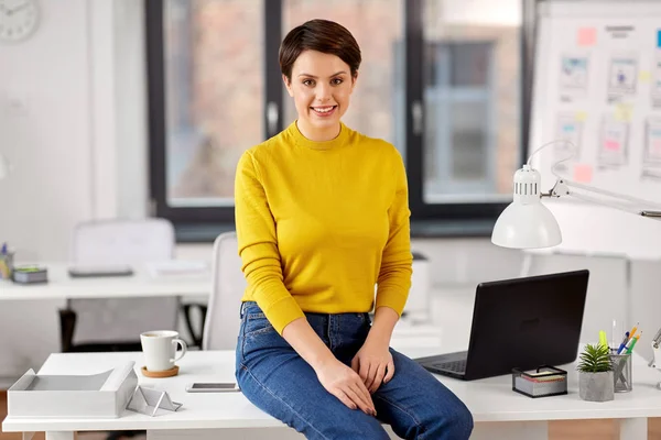 Happy businesswoman sitting on desk at office — Stock Photo, Image