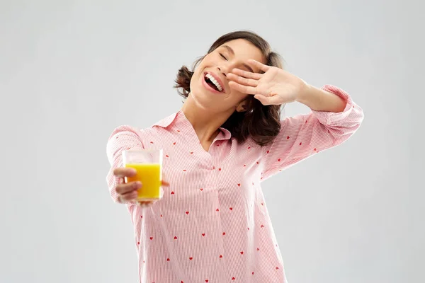 Happy yawning young woman in pajama with juice — Stock Photo, Image