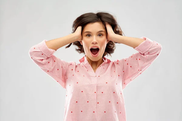 Overwhelmed young woman in pajama holding to head — Stock Photo, Image