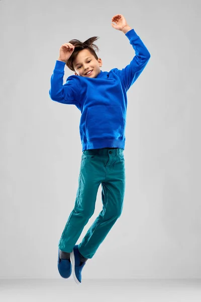 Retrato de menino sorridente com capuz azul pulando — Fotografia de Stock