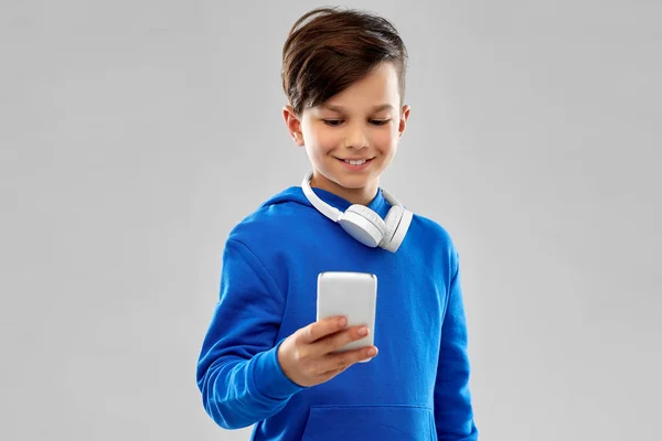 Menino sorridente com capuz azul usando smartphone — Fotografia de Stock