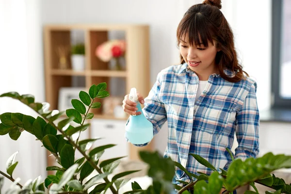 Heureux asiatique femme pulvérisation plante d'intérieur à la maison — Photo