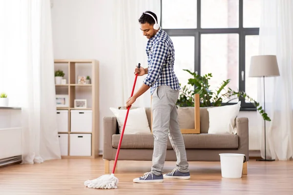 Evde paspas Temizleme zemin ile kulaklık adam — Stok fotoğraf