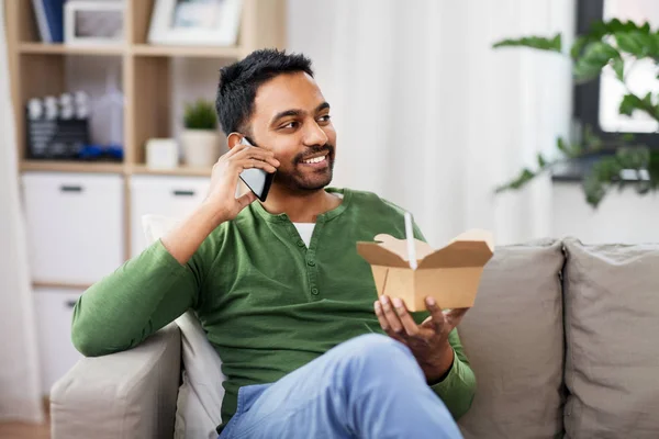 Hombre indio sonriente comiendo comida para llevar en casa — Foto de Stock