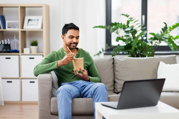 Uomo indiano con laptop mangiare cibo da asporto a casa — Foto Stock